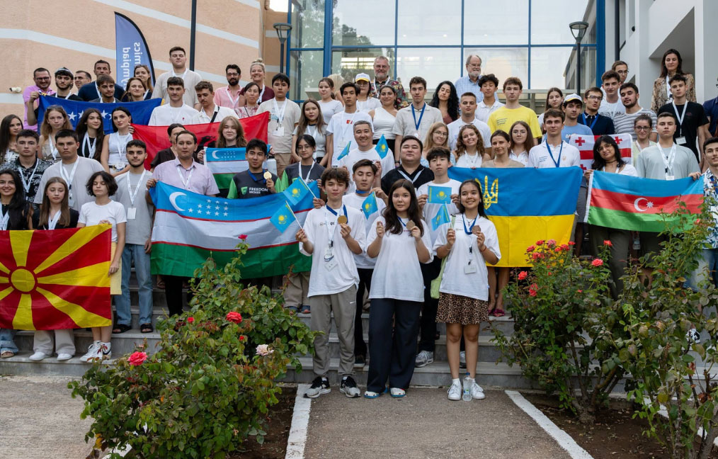 Several groups of students stood outside proudly holding their country flags and medals from the Economics Olympiad