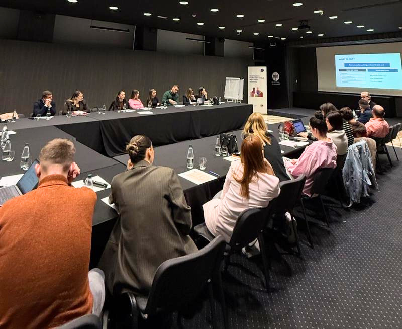 Event space with teachers sitting around a large table, all of them looking at a projector screen
