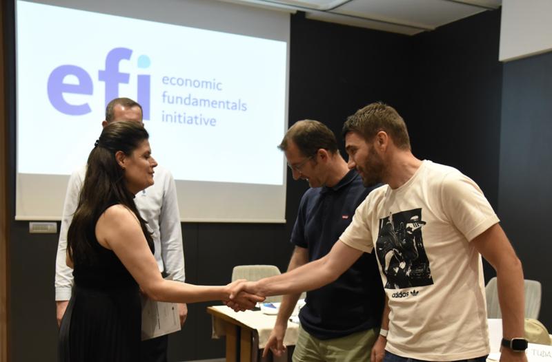 A group of four adults shaking hands in a EFI workshop