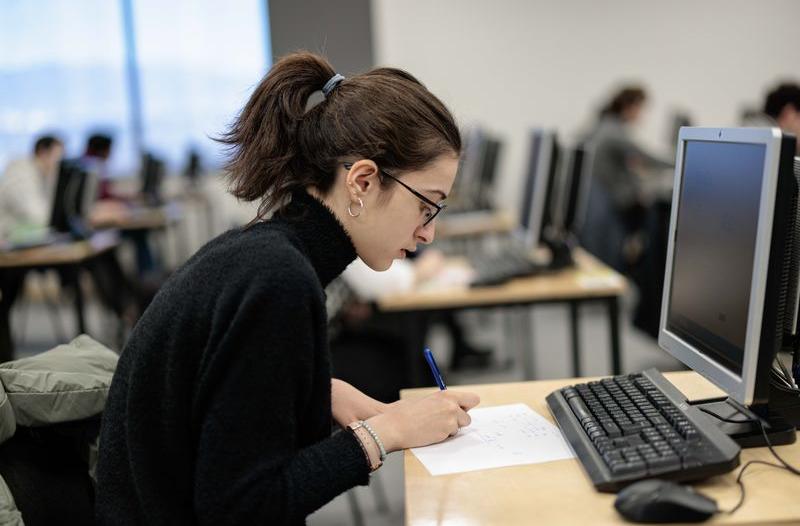 Side-on image of a student at her desk writing on a piece of paper