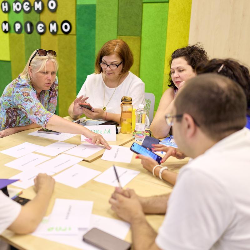 Teachers in a training workshop sat around a table collaborating