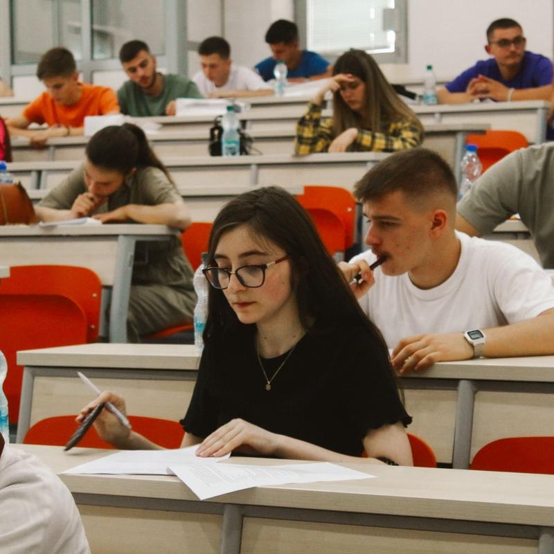Students in a lecture hall focused on their papers and desks