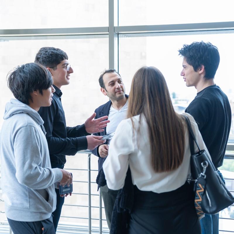 Five students in a corridor speaking to each other animatedly