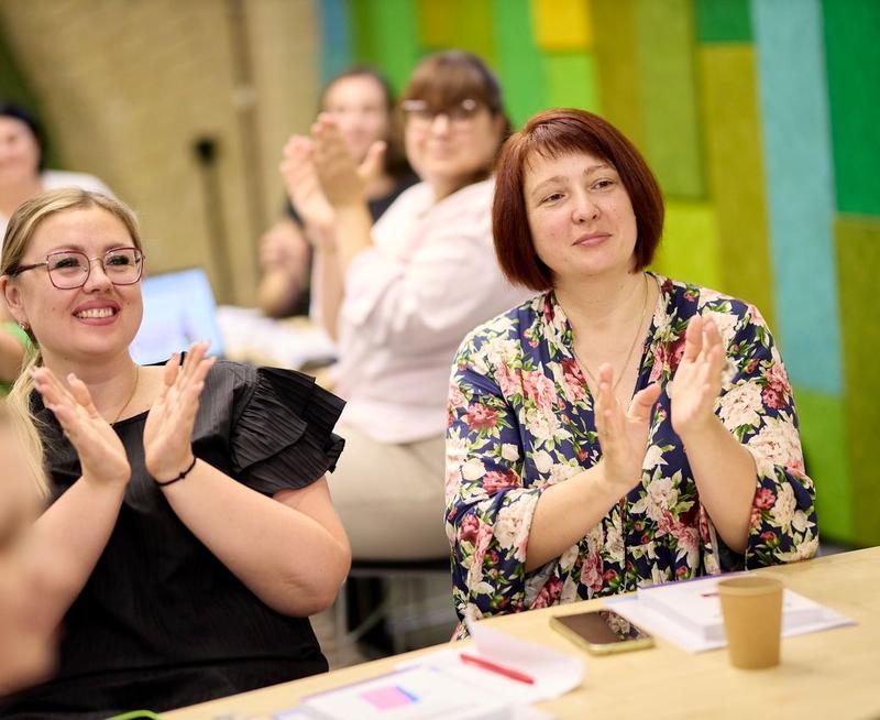 Two female teachers sat at a table and applauding